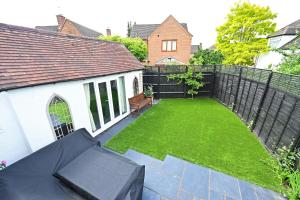 un pequeño patio trasero con una valla negra y césped en Central Townhouse with FREE onsite EV parking, en Stratford-upon-Avon
