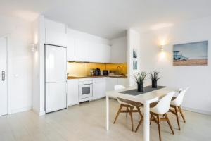 a kitchen with white cabinets and a table and chairs at Apartamento WELCS EMP 004 con inmejorables vistas in Empuriabrava