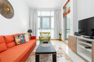 a living room with a orange couch and a tv at Vacay Lettings - 1 Bed at Iris Blue, Dubai Marina in Dubai