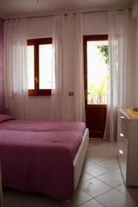 サン・ヴィート・ロ・カーポにあるAppartamento Antaresのベッドルーム1室(紫色のベッド1台、窓2つ付)