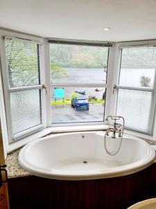 un bagno con vasca e ampia finestra di The Coylet Inn by Loch Eck a Dunoon