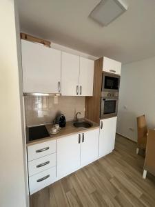 una cocina con armarios blancos y fregadero en Apartment Hana, en Dobra Voda