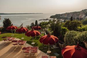 a group of red umbrellas and chairs and the water at Villa Bellevue Portoroz-Portorose in Portorož