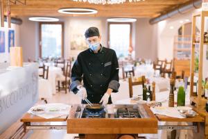 a chef preparing food on a stove in a restaurant at BACCO D'ORO Wine & Relais in Mezzane di Sotto