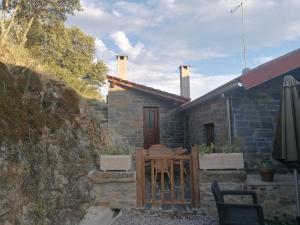 mały kamienny dom ze stołem i krzesłami w obiekcie Casa do Bonifácio w mieście Vilarinho