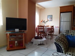 a living room with a flat screen tv and a table at AMISIANA HOUSE in Kavála