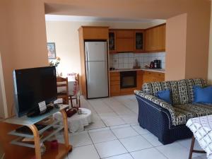 a living room with a tv and a kitchen at AMISIANA HOUSE in Kavála