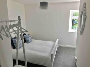 a white bedroom with a bed and a window at A woodland retreat - Apartment in converted mill in Helston