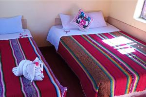 two twin beds in a room with at Hospedaje Rural La Florida en Llachon, Titicaca in Puno