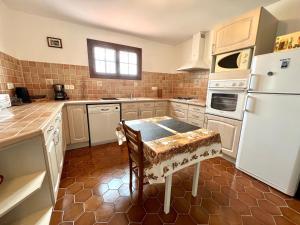 een keuken met een tafel en een witte koelkast bij Villa Chante Grive in Taradeau