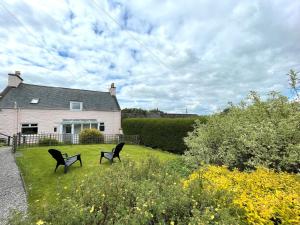 due panche sedute sull'erba di fronte a una casa di Pass the Keys Spacious 3BR Cottage in Beautiful Rural Setting a Castle Douglas