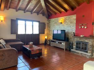un soggiorno con divano, TV e camino di RINCÓN DE DORA a La Pesa