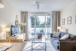 a living room with a blue couch and a glass table at Villa Kurpark in Zingst