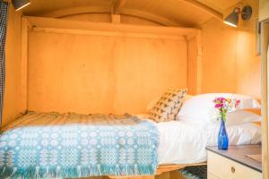 ein Schlafzimmer mit einem Bett und einer Vase mit Blumen in der Unterkunft Empress En Suite Wagon in Arthog