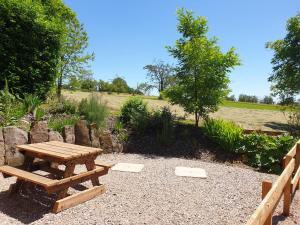 a wooden picnic table and a fence in a field at Les Vergers d'Epona "Fougerolles Haute-Saône" in Fougerolles