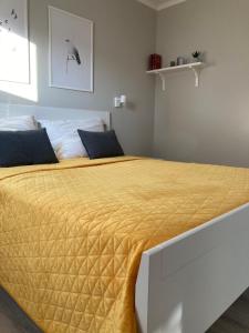 a bedroom with a large bed with a yellow blanket at Rizling Apartmanház**** Balatonalmádi in Balatonalmádi