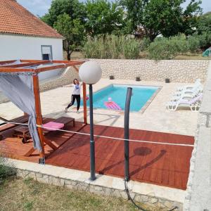 a woman playing a game of volleyball in a pool at Holiday House DA & DO in Pakoštane