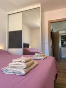 2 empiècements de serviettes assises sur un lit violet dans l'établissement Apartmani Antonia, à Račišće