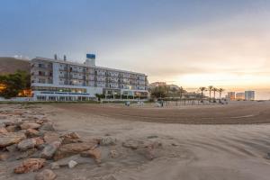 a building on the beach with rocks in front of it at Hotel Sicania in Cullera