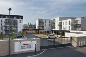a view of a parking lot with white buildings at Domitys La Fleur de Lin in Landerneau