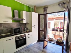 - une cuisine avec des placards blancs et un mur vert dans l'établissement Domus Rubra, à Castelsardo