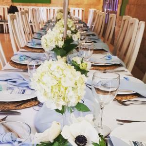 una mesa larga con flores blancas y copas de vino en Hostal Restaurante Dulcinea de El Toboso, en El Toboso