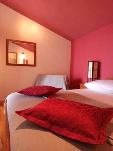 a bedroom with two beds with red walls and a mirror at Guest House Mijo Sokol in Brela