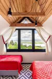 a bedroom with a red bed and a large window at FAJNE CHATY - rodzinny wypoczynek w górach in Falsztyn