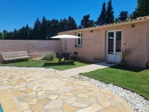 a patio with a bench and a table and an umbrella at Tylyan in Le Thor