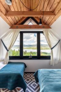 two beds in a room with a large window at FAJNE CHATY - rodzinny wypoczynek w górach in Falsztyn