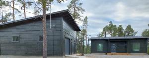 une maison noire avec un arbre en face dans l'établissement Villa Paatari, Inari (Paadarjärvi), à Inari