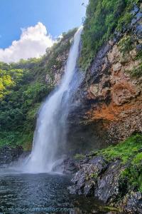 a waterfall on the side of a mountain next to a river at Pousada Três Forquilhas in Guananazes
