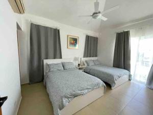 a bedroom with two beds and a ceiling fan at Fabulous Caracol Cadaques Caribe in Bayahibe