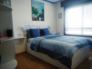 a bedroom with a bed with blue sheets and a window at Apt 40 m2 air conditioning radiant heating in Vigo