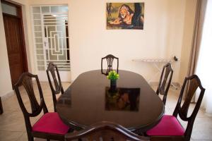 a dining room table with pink cushioned chairs and a table and a painting at Cottage in Nanyuki, Maiyan; Swara Ranch #28 in Nanyuki