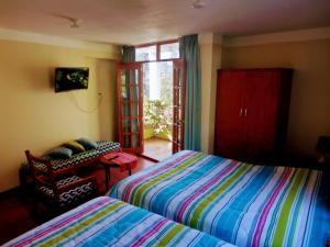 a bedroom with two beds and a chair and a window at Fundo San Silvestre in Huaraz