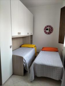 two beds in a small room with white cabinets at Rosa's Apartment with Terrace in Cagliari