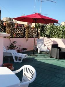 卡利亞里的住宿－Rosa's Apartment with Terrace，庭院配有白色椅子和红色遮阳伞