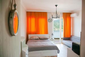 a bedroom with orange curtains and a bed and a couch at Жемчужина у моря in Batumi