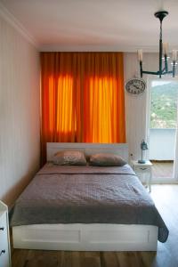 a bedroom with a bed with an orange curtain at Жемчужина у моря in Batumi