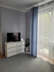 a living room with a tv on a dresser and a window at Apartament City Center in Łańcut