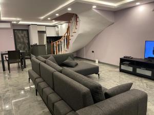 a living room with couches and a tv and a staircase at Özel havuz ve deniz manzaralı yeni villa in Kusadası