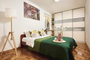 a bedroom with a bed with a green blanket at Lumina I Spacious 3BR Apartment with Parking I Balcony I Warszawa Zachodnia in Warsaw