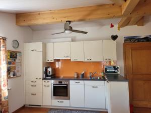 uma cozinha com armários brancos e uma ventoinha de tecto em Ferienwohnung Bally em Brunnen