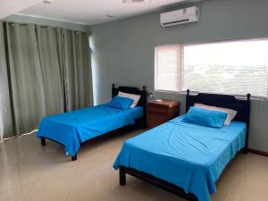 two beds in a room with blue sheets and a window at MountView studio in city in Port Louis