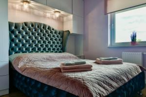 a bedroom with a bed with a tufted headboard and two pillows at Apartament32 Golden Vip -Duże Miejsce Postojowe- in Olsztyn
