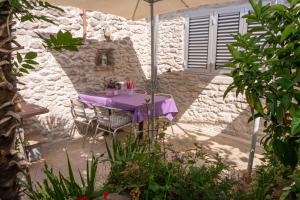 una mesa púrpura y sillas bajo una sombrilla en Eleonora Apartments, en Zadar