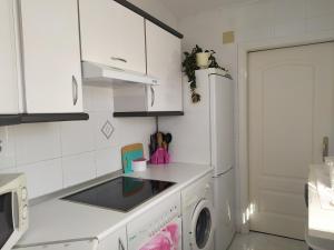 a kitchen with white cabinets and a washer and dryer at Apartamento junto a la Basilica del Pilar in Zaragoza
