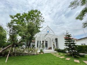 Biały dom z zielonym dziedzińcem w obiekcie Me and Tree Villa w mieście Kaeng Khoi