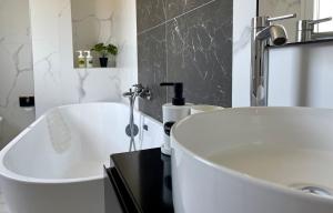 a white bathroom with a tub and a sink at Vila Llanaj in Ksamil